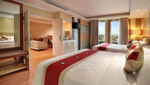 A hotel room with two beds, a desk, a TV, and a view of the city.