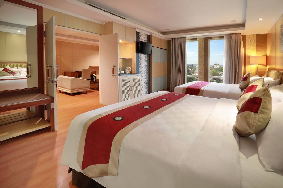 Habitación de hotel con dos camas, un escritorio, televisión y vistas a la ciudad.