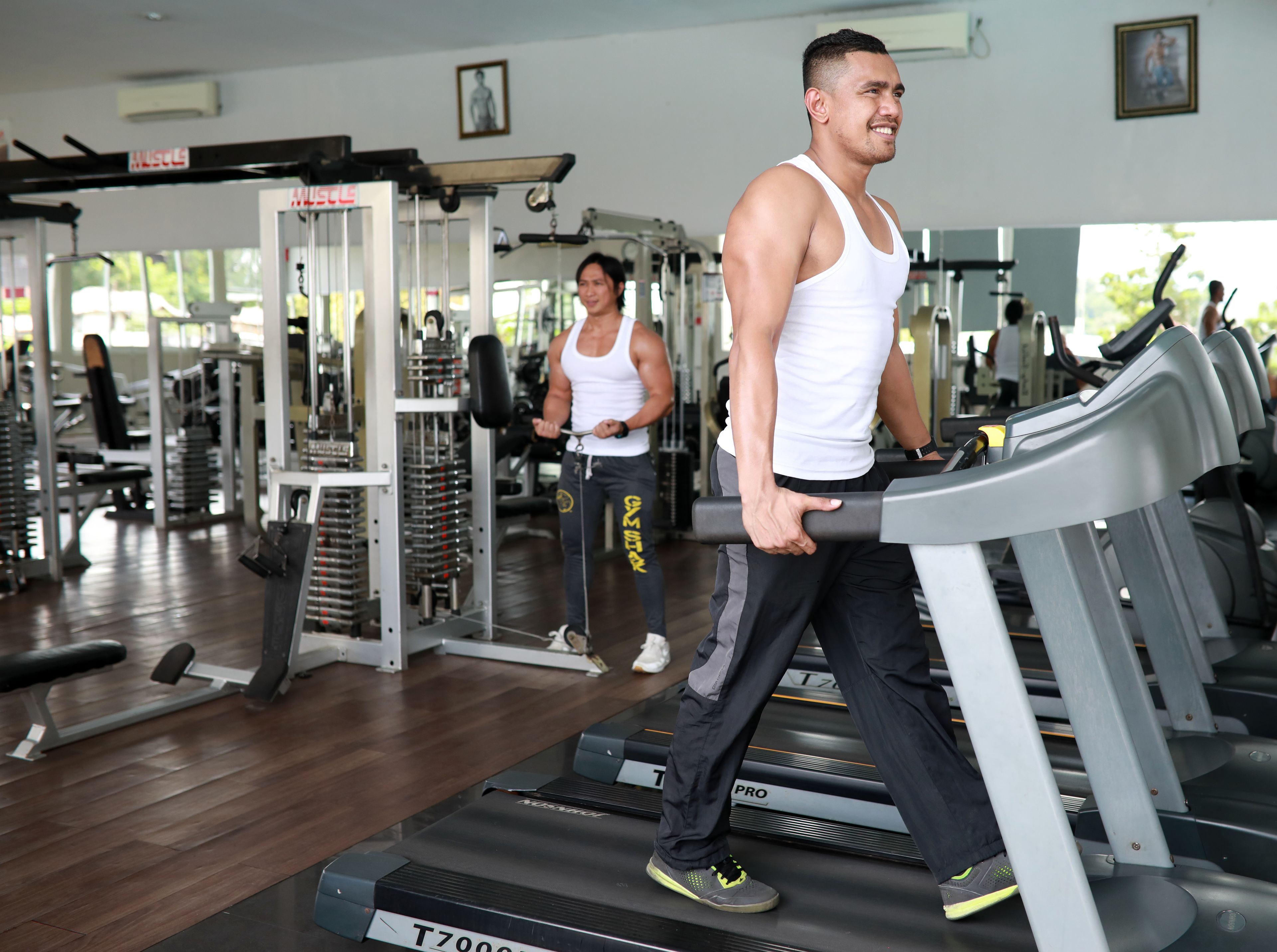 A gym with treadmills, weight machines, and a person using a treadmill.