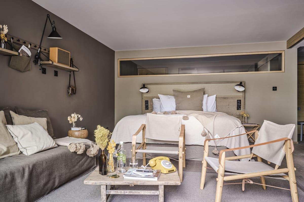 Quarto moderno com uma cama grande, mesas de cabeceira, uma escrivaninha e uma cadeira.