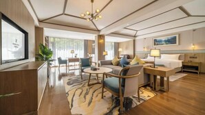 A modern hotel room with a sofa set, a dining table, a TV, and a bed. - Qianhe Rezen Hotel (Jiuzhaigou)