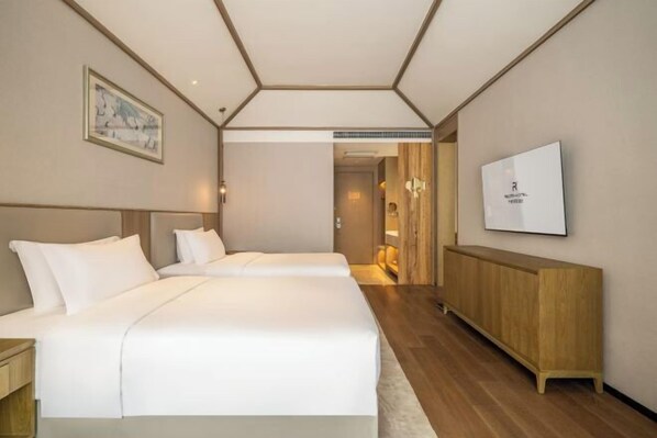 A hotel room with two beds, a wooden cabinet, a television, and a framed picture on the wall. - Qianhe Rezen Hotel (Jiuzhaigou)