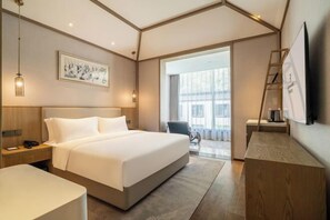 A modern hotel room with a large bed, bedside tables, a desk, and a TV. - Qianhe Rezen Hotel (Jiuzhaigou)