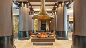 A lobby with a central fire feature, wooden columns, and a seating area. - Qianhe Rezen Hotel (Jiuzhaigou)