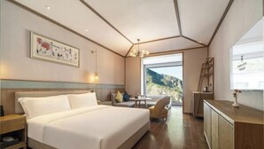 A modern hotel room with a large bed, a desk, a chair, and a view of the outdoors. - Qianhe Rezen Hotel (Jiuzhaigou)