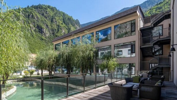 A modern hotel with a pool, outdoor seating, and mountain views. - Qianhe Rezen Hotel (Jiuzhaigou)