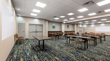 A conference room with a patterned carpet, multiple tables and chairs, and a whiteboard.