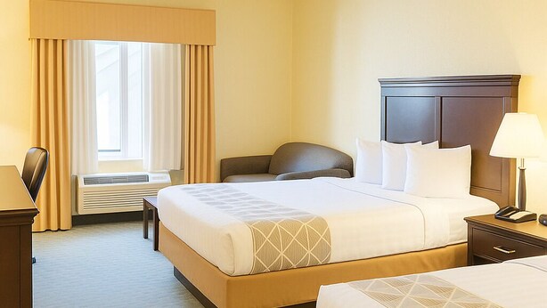 Une chambre d’hôtel avec un grand lit, un lit plus petit, un bureau et une chaise.