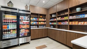 Une épicerie dotée de rayons réfrigérés, d’étagères remplies d’en-cas et de boissons, et d’armoires en bois.