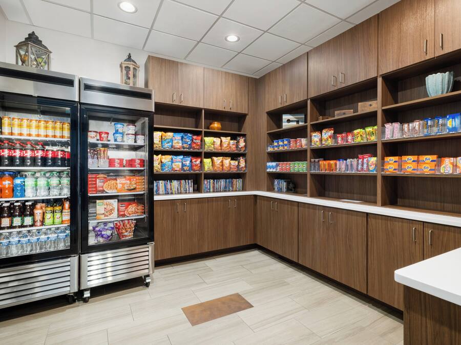 A grocery store with refrigerated sections, shelves stocked with snacks and beverages, and wooden cabinets.