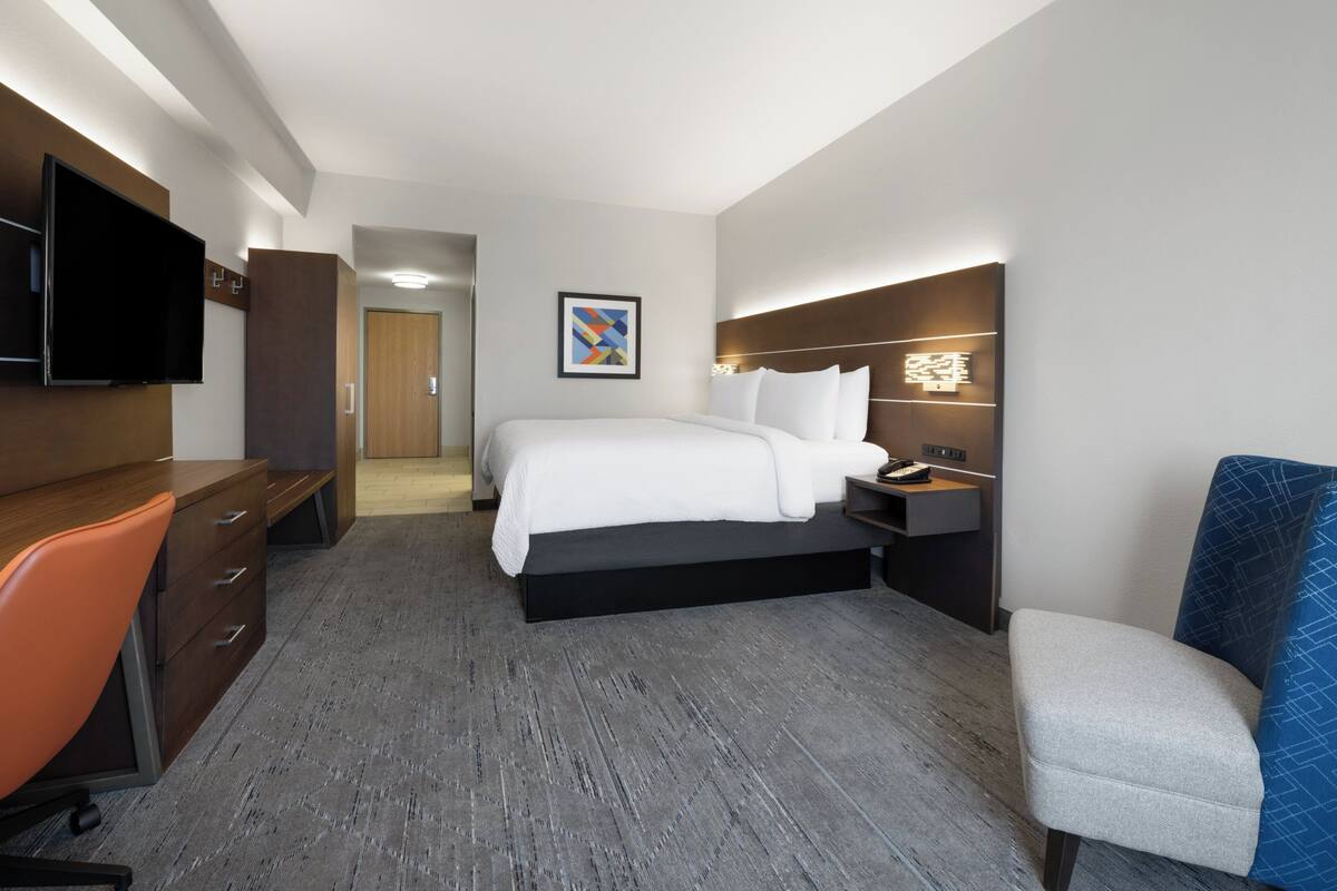 Ein Hotelzimmer mit Bett, Schreibtisch, Stuhl, Fernseher und Bildern an der Wand.