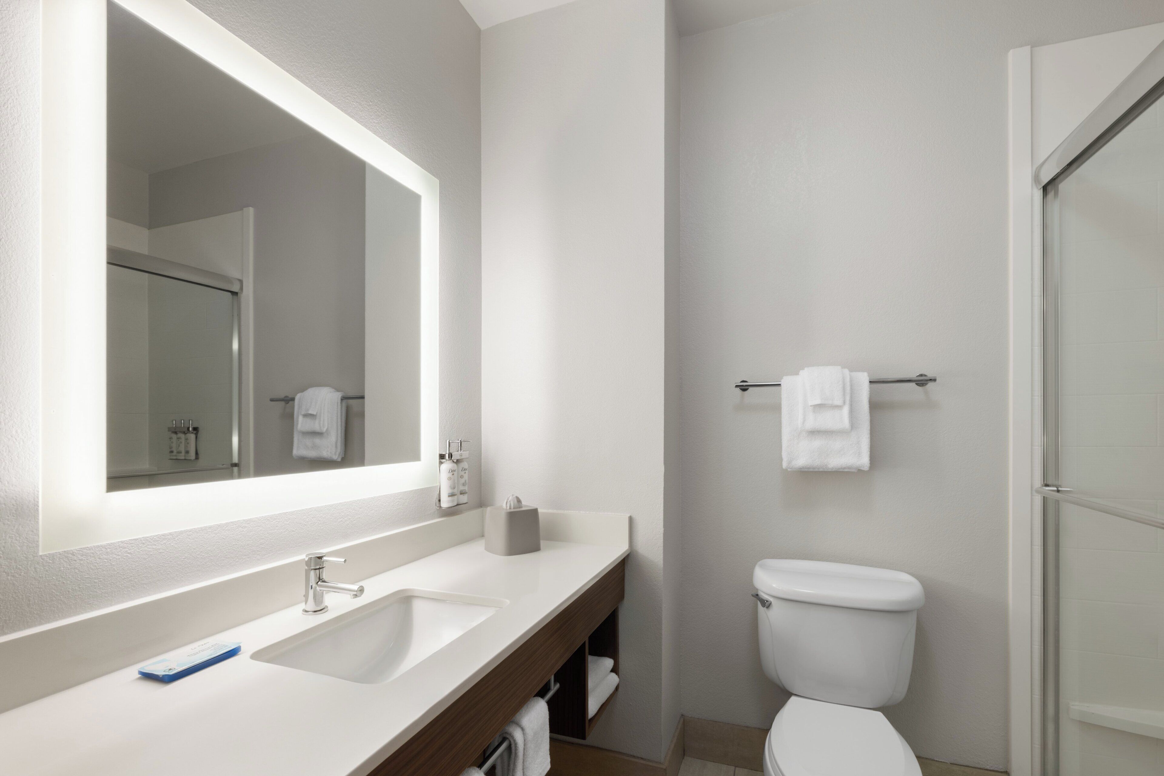 Une salle de bain avec un lavabo blanc, un miroir et des toilettes.