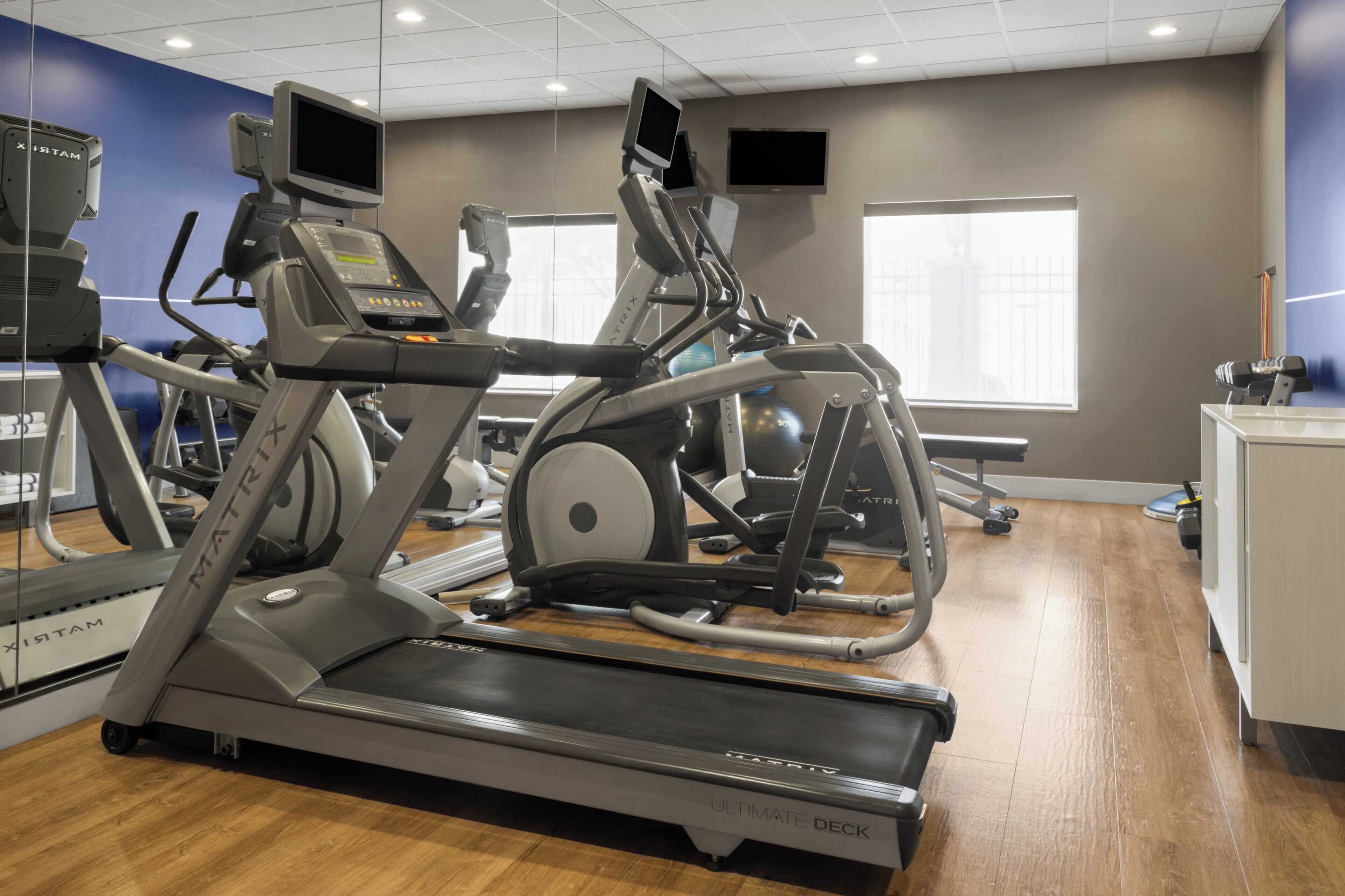 Ein Fitnessstudio mit Laufbändern, Crosstrainern und Gymbällen.