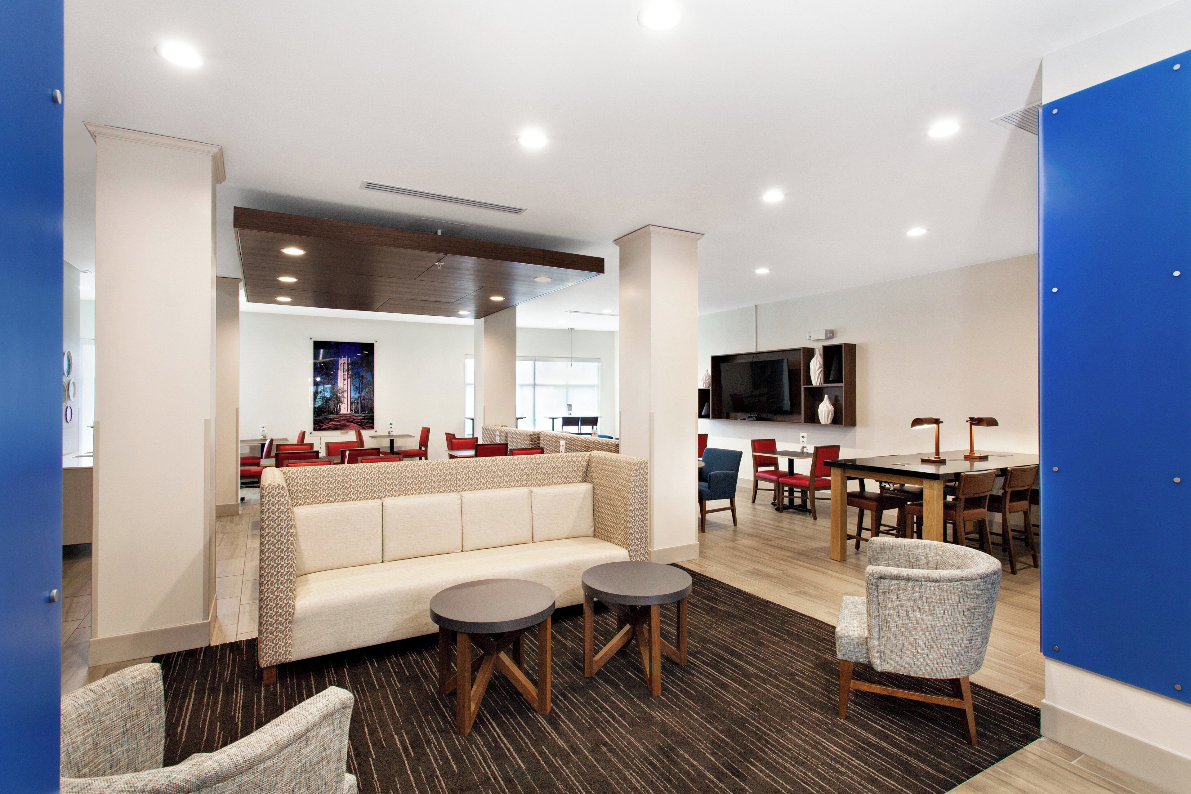 A modern lounge area with a sofa, two round tables, and chairs.