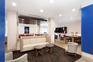 A modern lounge area with a sofa, two round tables, and chairs. - Holiday Inn Express Lake Wales N-Winter Haven by IHG (Lake Wales)