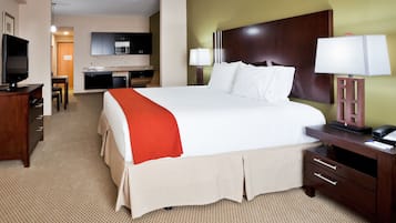 A hotel room with a large bed, a desk, a television, a lamp, and a microwave in the background.