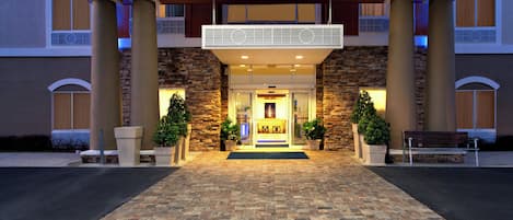 A hotel entrance with a stone facade, a double entrance, and a welcoming reception area.