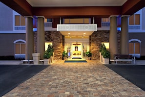 L’entrée d’un hôtel, avec une façade en pierre, un double portail et un espace d’accueil chaleureux.