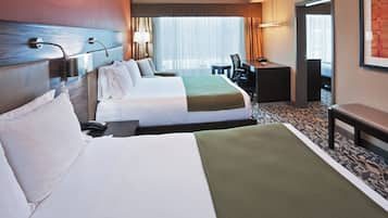 Une chambre d’hôtel avec deux lits, un bureau, une chaise et une fenêtre avec des rideaux.