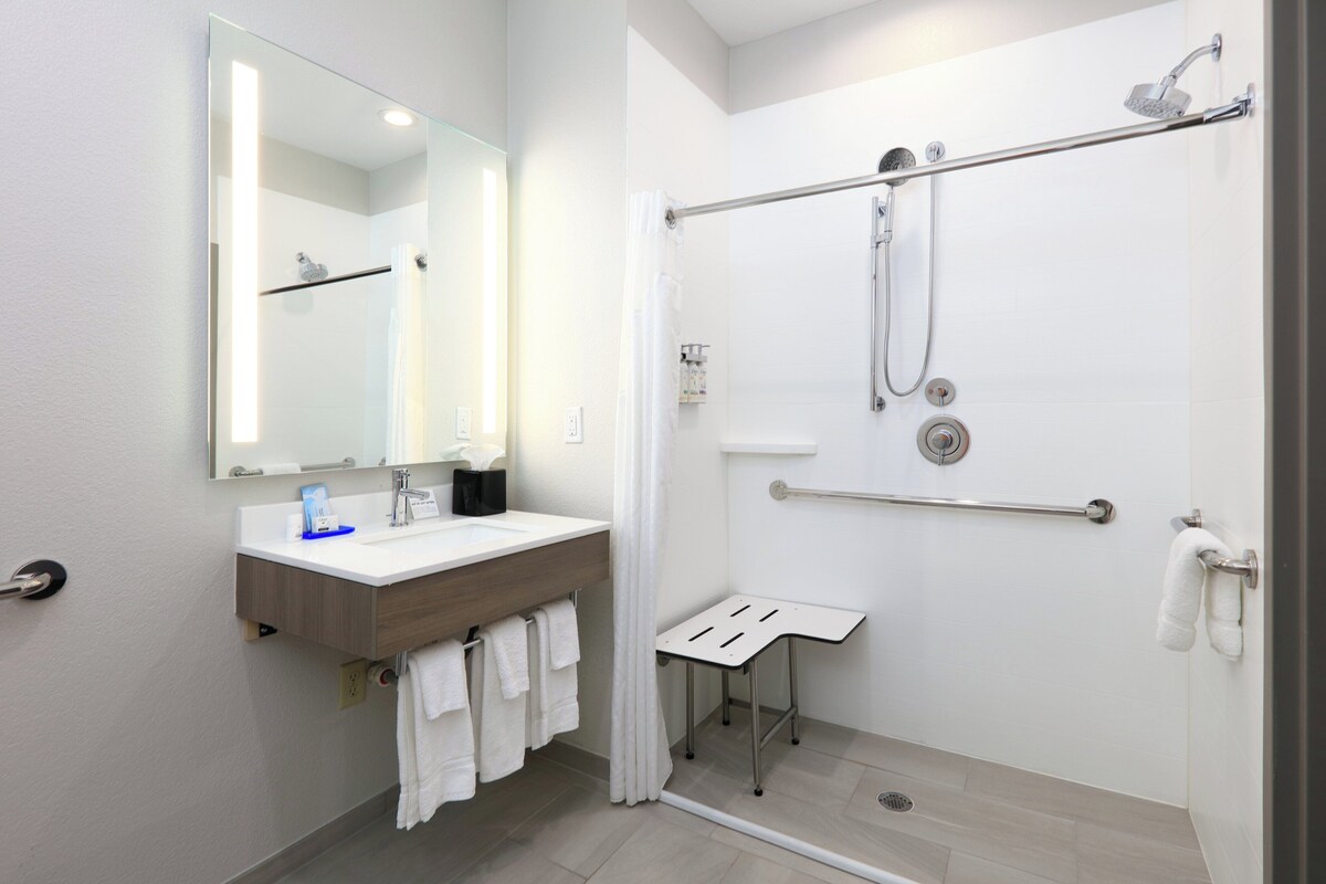 A modern bathroom with a shower, a sink, a mirror, and a towel rack.
