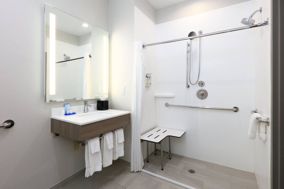 A modern bathroom with a shower, a sink, a mirror, and a towel rack.