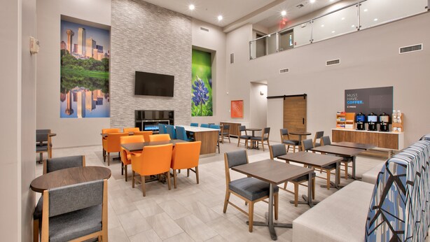 A modern hotel lobby with seating areas, a fireplace, and a coffee station. - Holiday Inn Express & Suites North Dallas at Preston by IHG (Dallas)