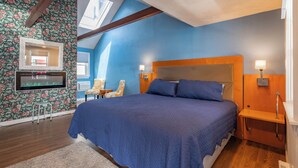 A bedroom with a large bed, a TV mounted on the wall, and a skylight. - Jonathan Edwards Motel (Dennis Port)
