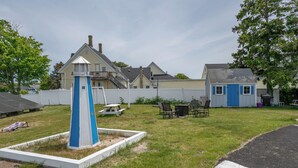 A residential area with a blue and white lighthouse-like structure, a picnic table, and outdoor seating. - Jonathan Edwards Motel (Dennis Port)