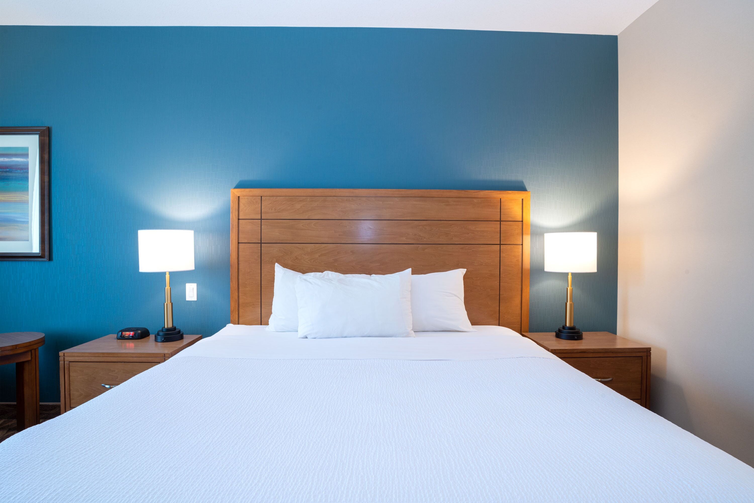 Une chambre d’hôtel avec un grand lit, deux tables de chevet et deux lampes.