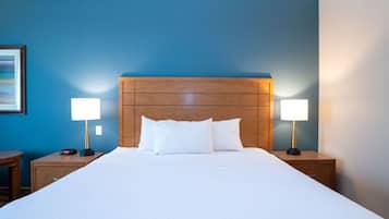 Une chambre d’hôtel avec un grand lit, deux tables de chevet et deux lampes.