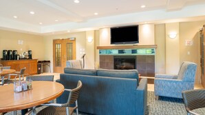 A hotel lobby with a seating area, a fireplace, a television, and a coffee station. - Sandman Hotel & Suites Squamish (Squamish)