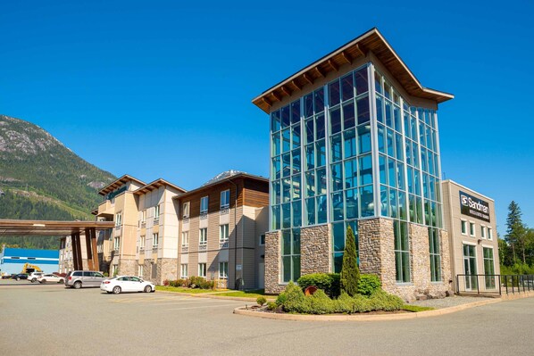 A hotel with a modern glass facade, a stone base, and a wooden roof.