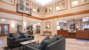 A spacious lobby with a high ceiling, a reception desk, and a seating area with sofas and a coffee table. - Sandman Hotel & Suites Squamish (Squamish)