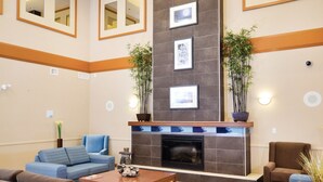 A modern lobby with a fireplace, seating area, and decorative mirrors. - Sandman Hotel & Suites Squamish (Squamish)