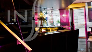 A modern hotel interior with a central bar area, a staircase, and a view of the outside. - Hotel Inffinit (Vigo)