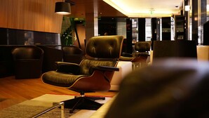 A modern hotel lobby with leather chairs, a reception desk, and a staircase in the background. - Hotel Inffinit (Vigo)