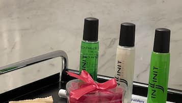 A tray with three bottles of hotel toiletries, a pink gift bag, and two brown paper bags.