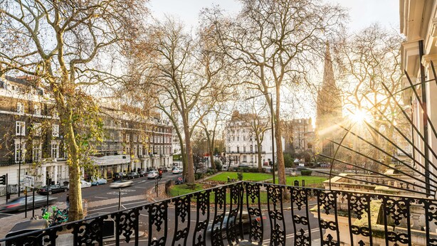 A balcony with a view of a city street, trees, and buildings. - Lancaster Court Hotel (London)