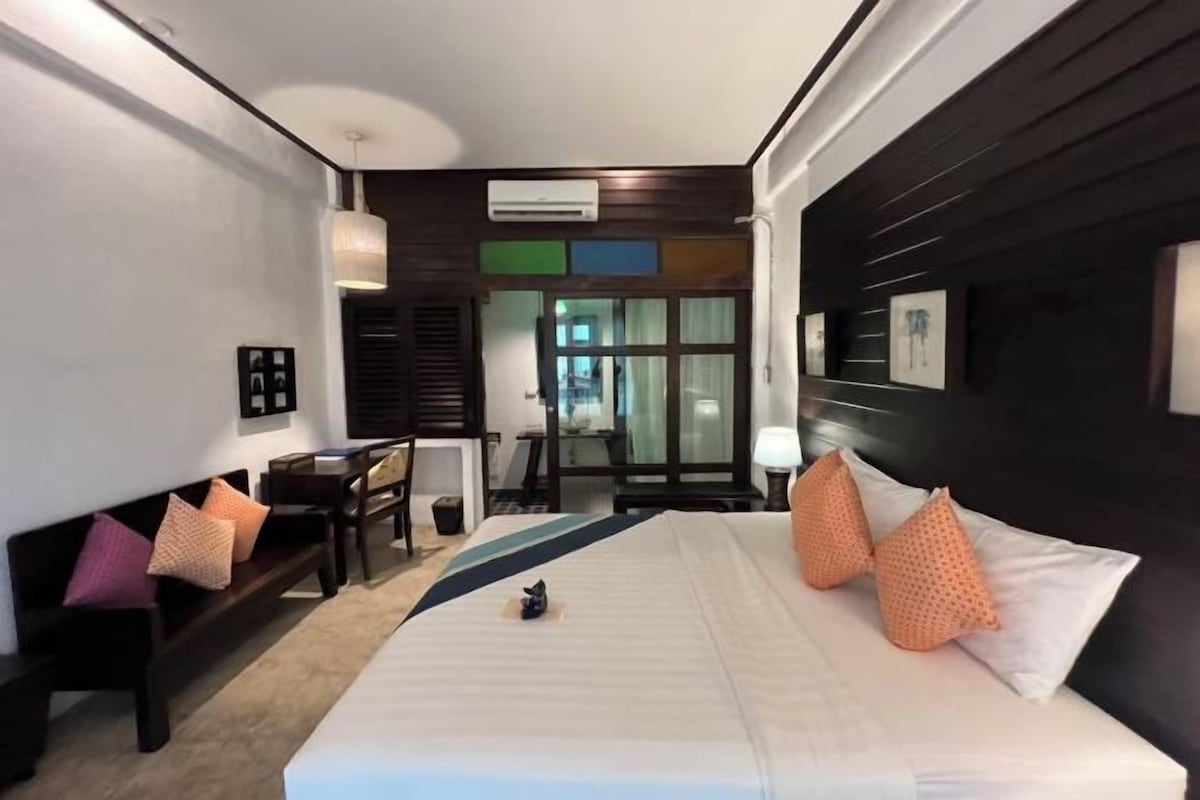 A hotel room with a bed, a desk, and a chair. There is a window with a view of the outside.