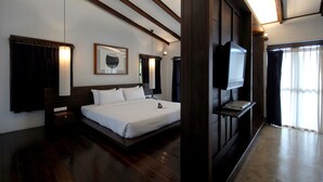 A hotel room with a large bed, a flat-screen TV mounted on the wall, and a wooden ceiling. - Banthai Village (Chiang Mai)