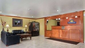A reception area with a Days Inn sign, a reception desk, a vending machine, two sofas, and a coffee table. - Days Inn by Wyndham Lumberton (Lumberton)