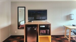 A compact room with a television on a wooden stand, a microwave below it, and a small refrigerator. - Days Inn by Wyndham Lumberton (Lumberton)
