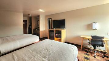 Habitación de hotel con dos camas, un escritorio, una silla, un televisor y un microondas.