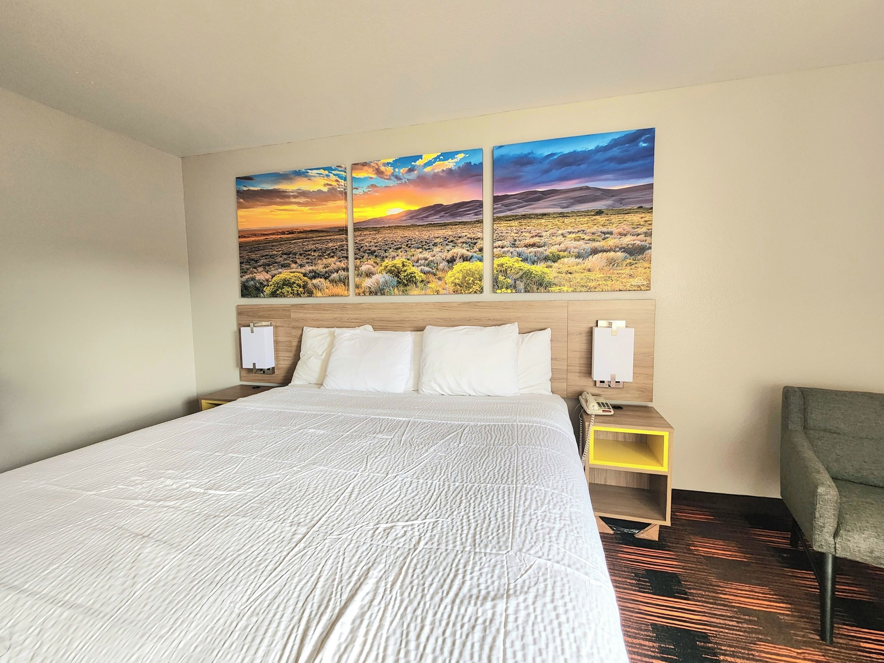 Habitació d'hotel amb un llit gran, una tauleta de nit amb un telèfon i una cadira.