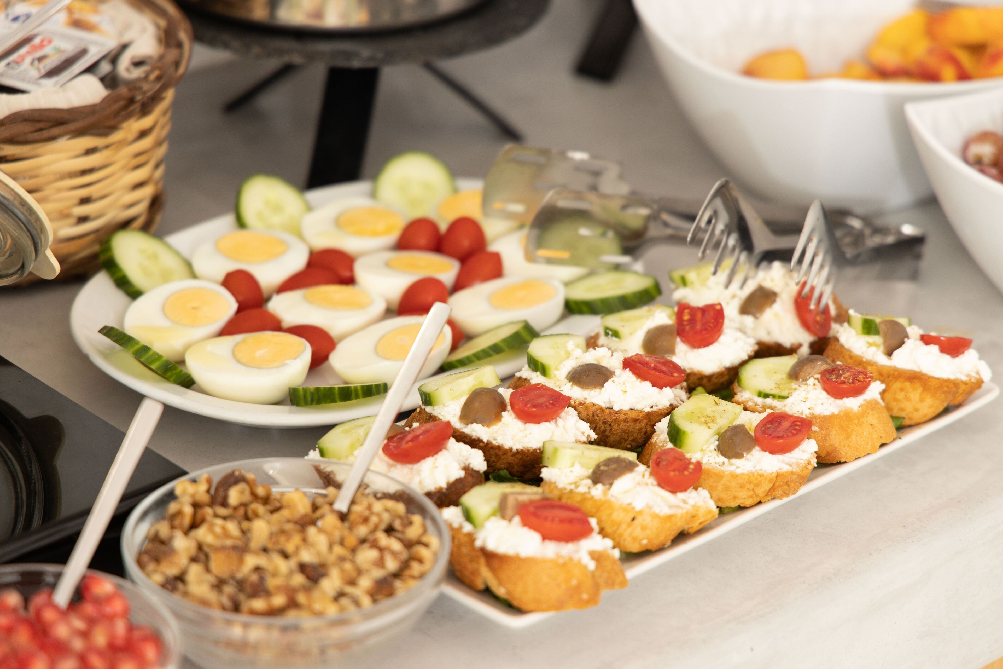 A buffet table with various food items including sliced cucumbers, tomatoes, and eggs.