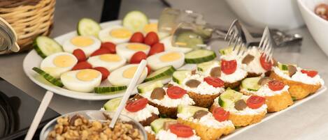 A buffet table with various food items including sliced cucumbers, tomatoes, and eggs.