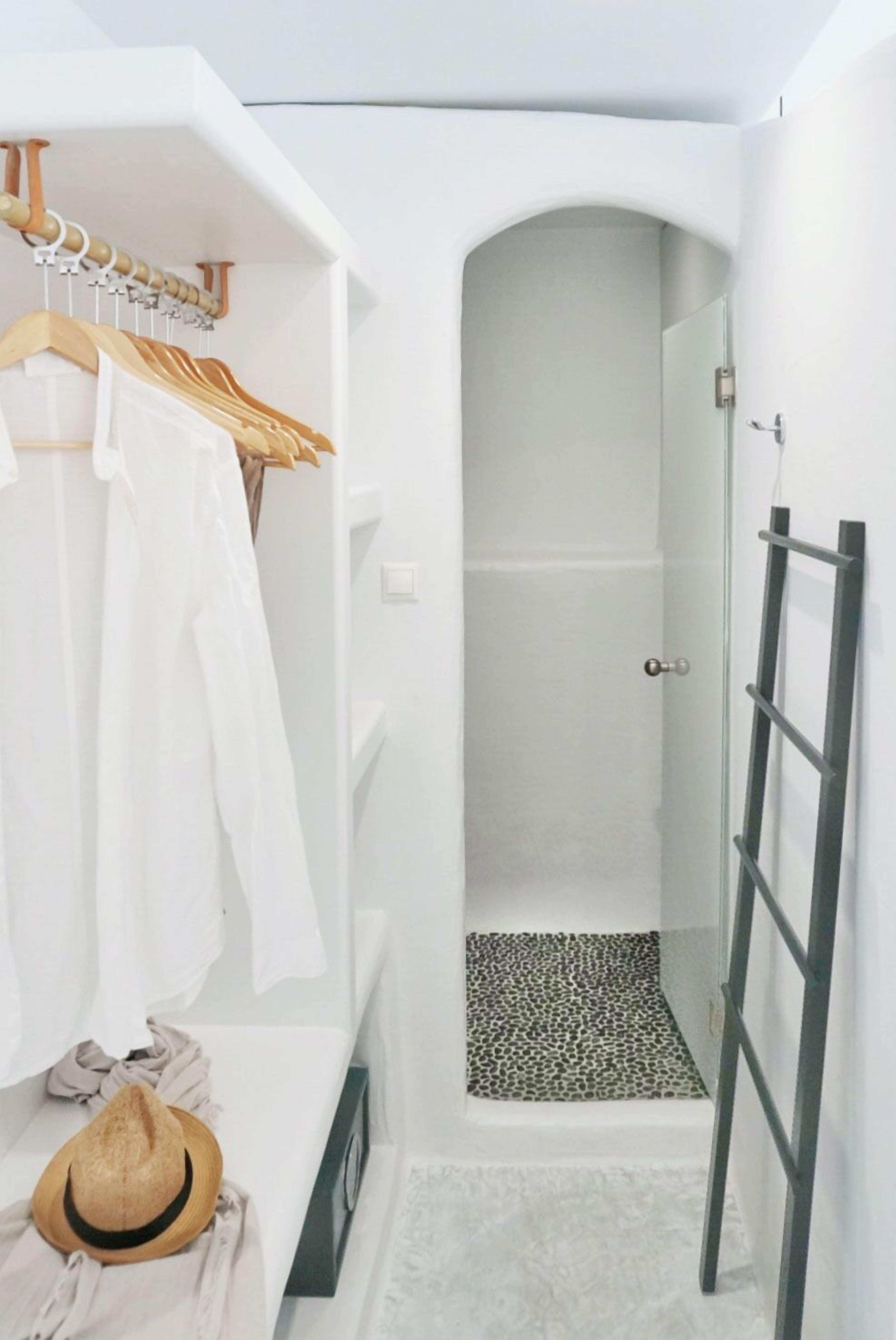 A bathroom with a shower, a towel rack with white towels, a hat on the floor, and a leopard print rug.