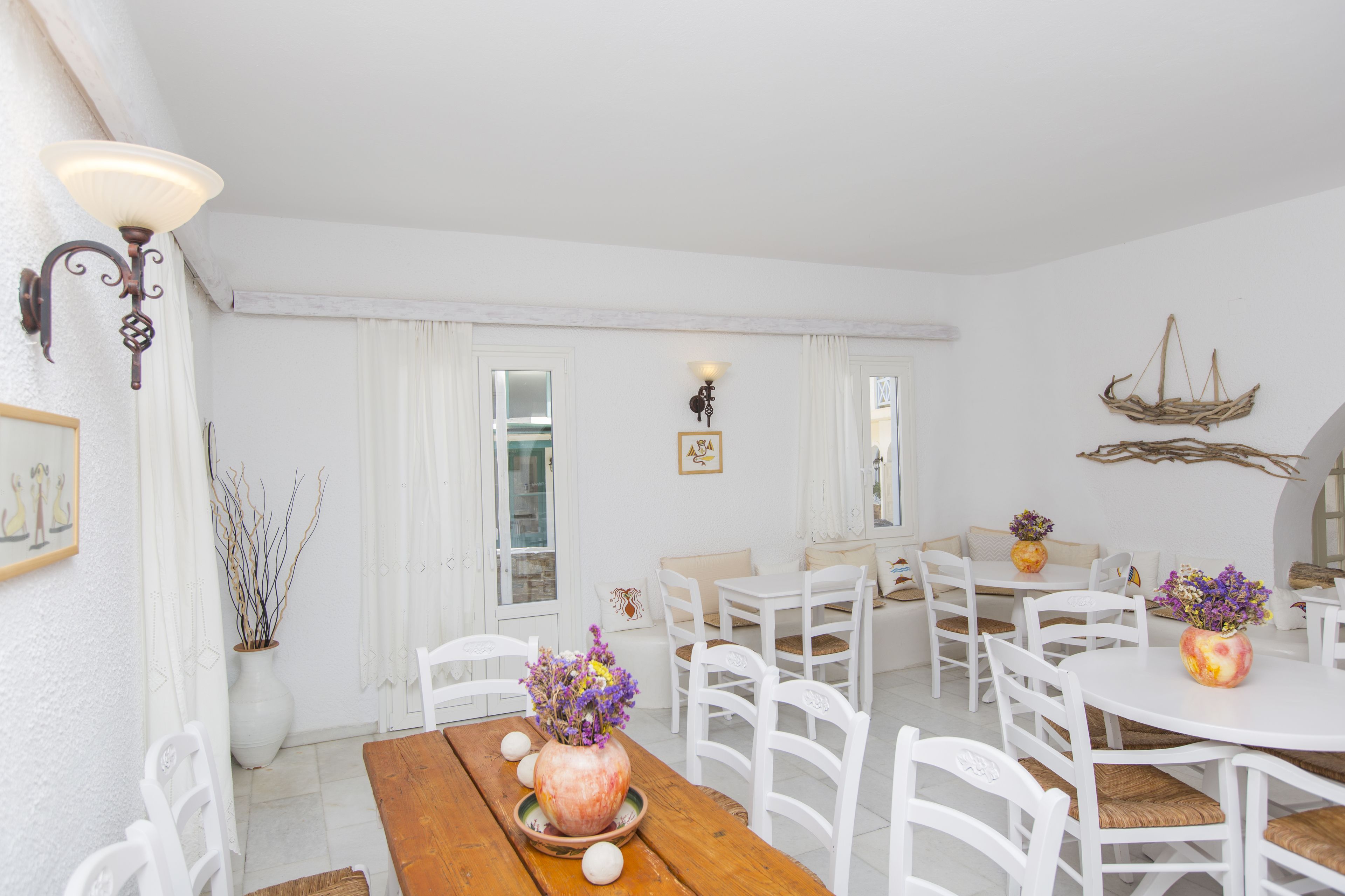 A dining area with white furniture, a wooden table, and a vase with flowers.
