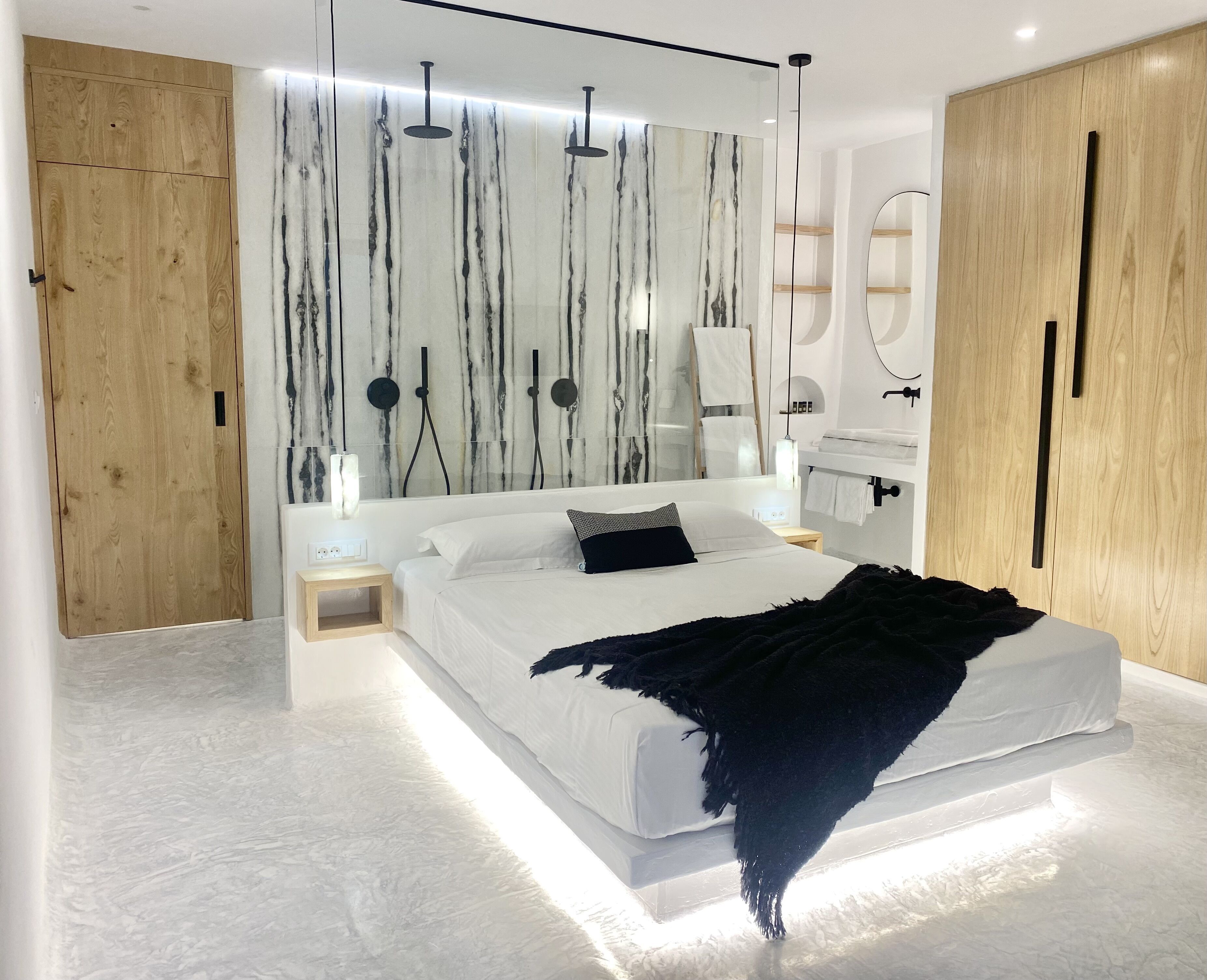 Un dormitorio moderno con una cama grande, un armario de madera y una pared de mármol.
