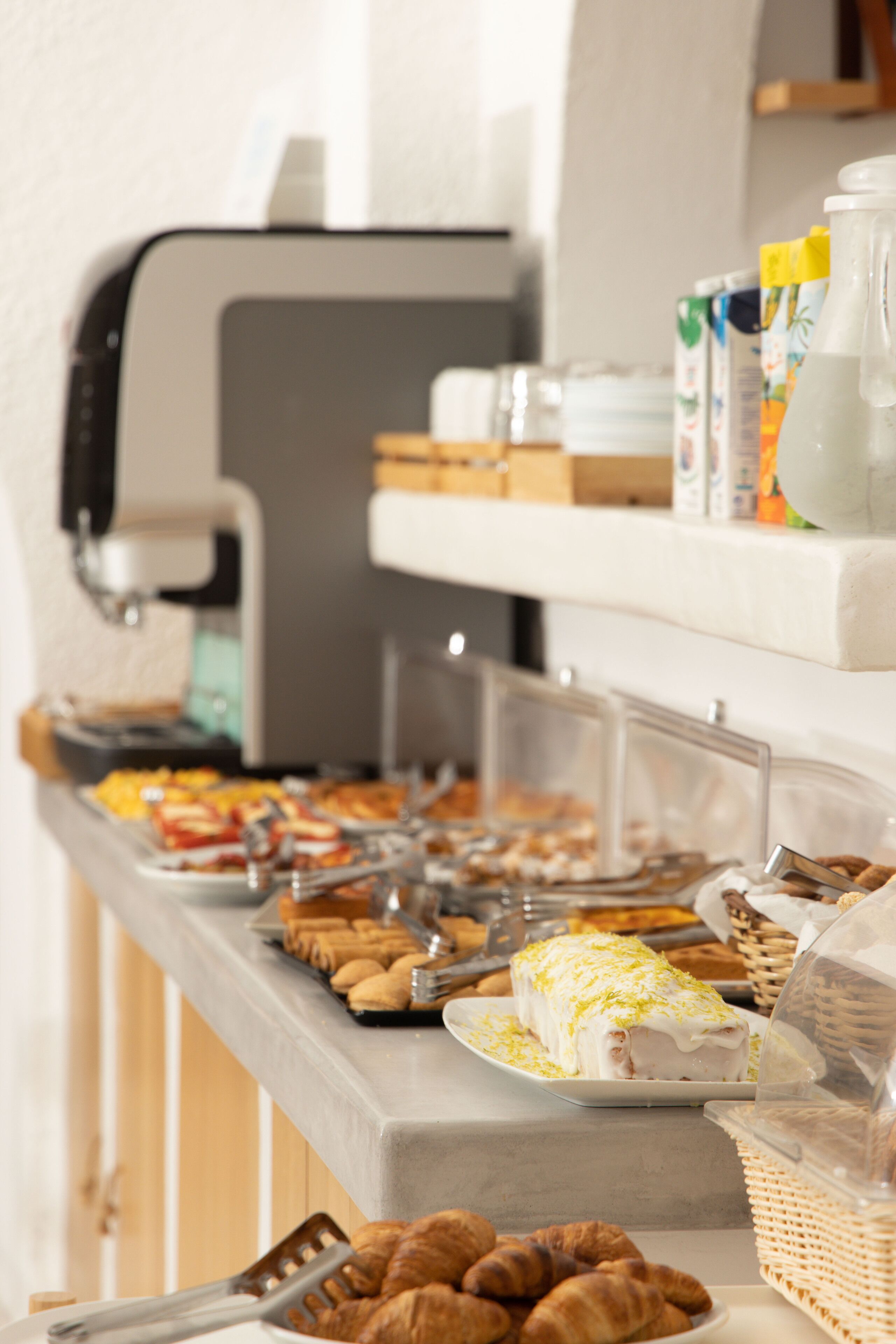 A buffet with various food items, including pastries and a coffee machine.